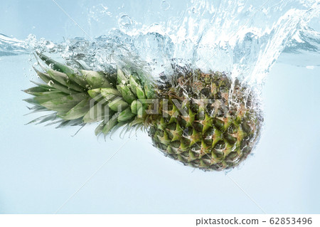 Exotic freshness. Juicy pineapple splashing into pure water on blue background Exotic freshness. Juicy pineapple splashing into pure water on blue background 62853496