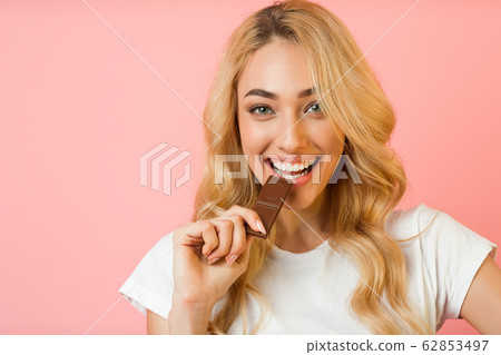 Cute woman biting piece of milk chocolate Cute woman biting piece of milk chocolate 62853497