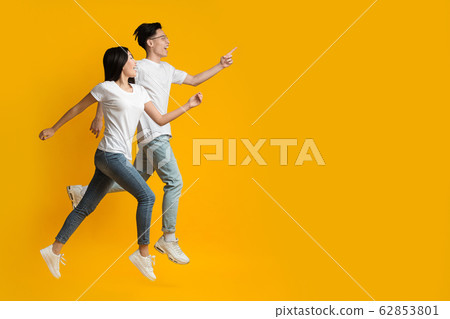 Excited asian couple running towards copy space Excited asian couple running towards copy space 62853801
