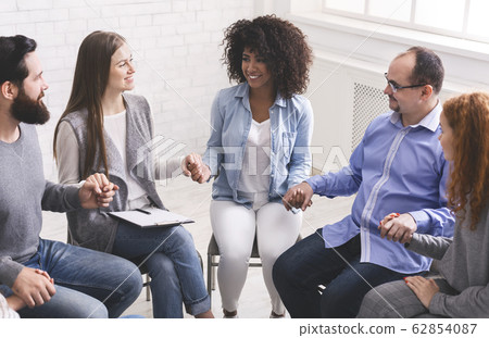 Young multi-cultural group of people holding hands during therapy session 62854087