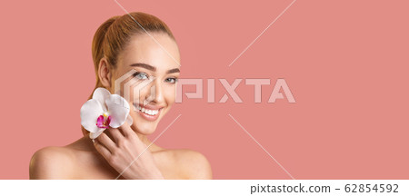 Girl Holding White Orchid Near Face Posing, Pink Background, Panorama Girl Holding White Orchid Near Face Posing, Pink Background, Panorama 62854592