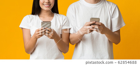 Cropped of asian man and woman using phones over yellow 62854688