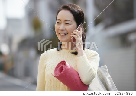 活躍的高級女子智能手機瑜伽 62854886