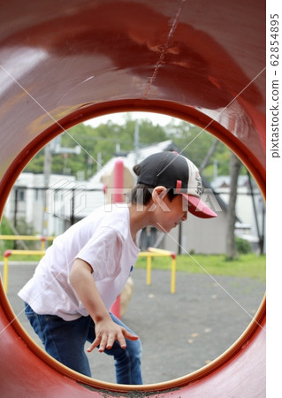 一名 5 歲男孩在公園遊樂設施的隧道外玩耍 62854895