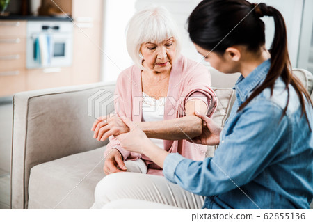 Female physician checking arm of elderly woman Female physician checking arm of elderly woman 62855136