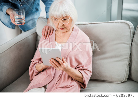 Old woman using digital tablet while spending time with granddaughter 62855973