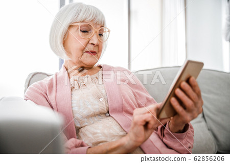 Senior lady using modern cellphone at home Senior lady using modern cellphone at home 62856206