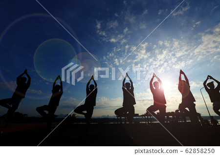 Silhouette of men train Yoga on lawn yard along Silhouette of men train Yoga on lawn yard along 62858250