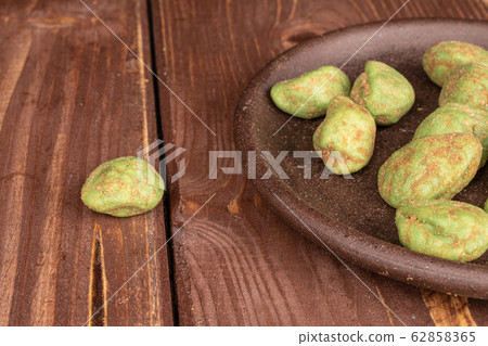 Green wasabi peanut on brown wood Green wasabi peanut on brown wood 62858365