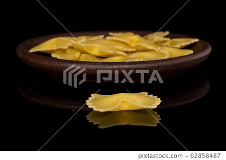 Yellow farfalle pasta isolated on black glass Yellow farfalle pasta isolated on black glass 62858487
