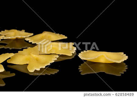 Yellow farfalle pasta isolated on black glass Yellow farfalle pasta isolated on black glass 62858489