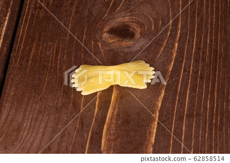 Yellow farfalle pasta on brown wood 62858514