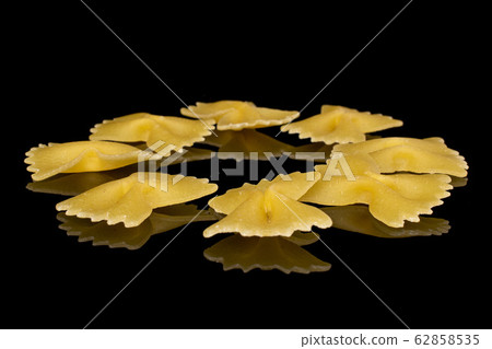 Yellow farfalle pasta isolated on black glass Yellow farfalle pasta isolated on black glass 62858535