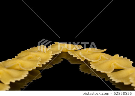 Yellow farfalle pasta isolated on black glass Yellow farfalle pasta isolated on black glass 62858536