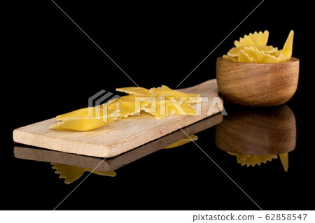 Yellow farfalle pasta isolated on black glass Yellow farfalle pasta isolated on black glass 62858547
