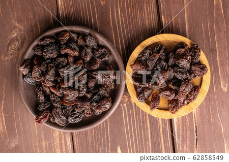 Dried dark raisin on brown wood Dried dark raisin on brown wood 62858549