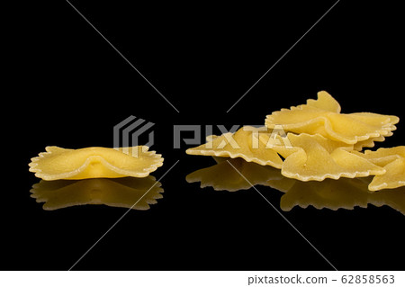 Yellow farfalle pasta isolated on black glass Yellow farfalle pasta isolated on black glass 62858563