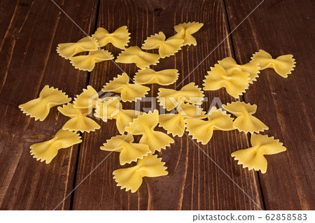 Yellow farfalle pasta on brown wood Yellow farfalle pasta on brown wood 62858583