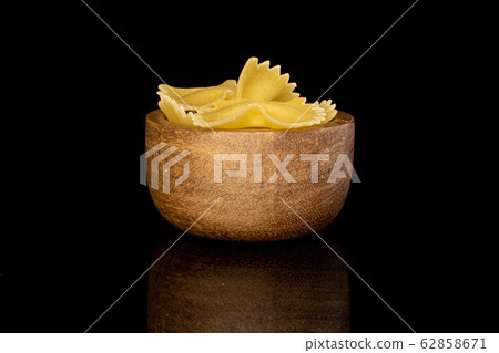 Yellow farfalle pasta isolated on black glass Yellow farfalle pasta isolated on black glass 62858671