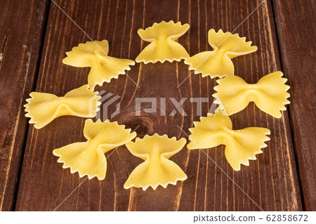 Yellow farfalle pasta on brown wood Yellow farfalle pasta on brown wood 62858672