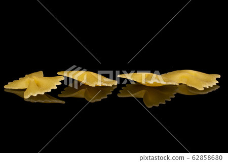 Yellow farfalle pasta isolated on black glass Yellow farfalle pasta isolated on black glass 62858680