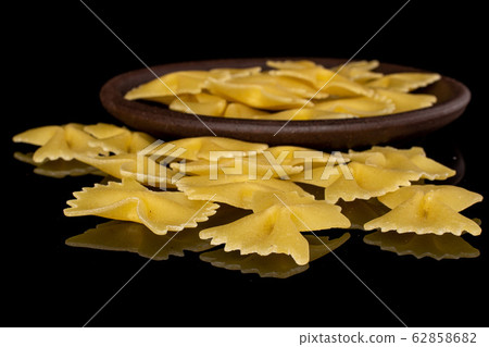 Yellow farfalle pasta isolated on black glass 62858682
