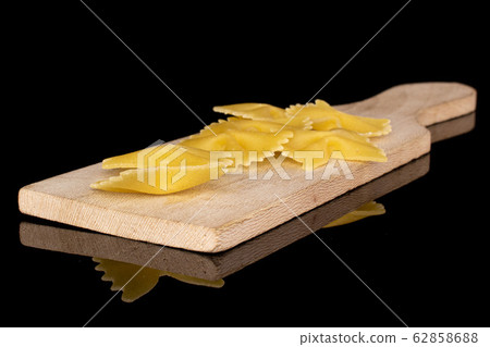 Yellow farfalle pasta isolated on black glass Yellow farfalle pasta isolated on black glass 62858688