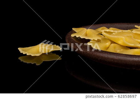 Yellow farfalle pasta isolated on black glass Yellow farfalle pasta isolated on black glass 62858697