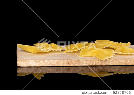 Yellow farfalle pasta isolated on black glass Yellow farfalle pasta isolated on black glass 62858706