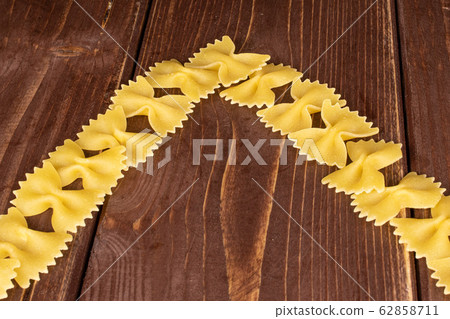 Yellow farfalle pasta on brown wood Yellow farfalle pasta on brown wood 62858711