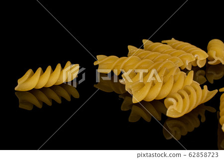 Yellow fusilli pasta isolated on black glass Yellow fusilli pasta isolated on black glass 62858723