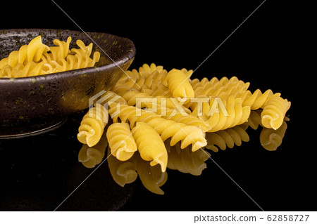 Yellow fusilli pasta isolated on black glass 62858727