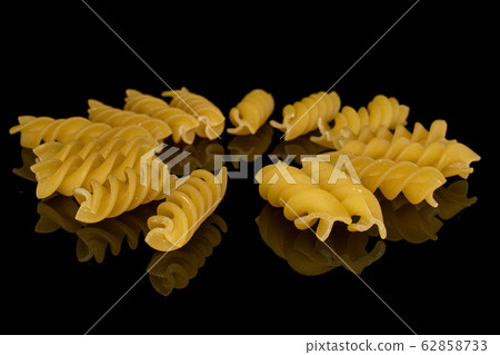 Yellow fusilli pasta isolated on black glass Yellow fusilli pasta isolated on black glass 62858733