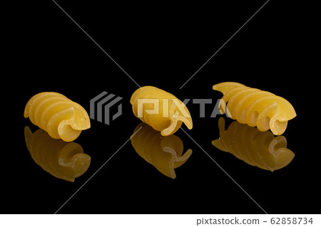 Yellow fusilli pasta isolated on black glass 62858734