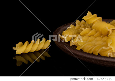 Yellow fusilli pasta isolated on black glass Yellow fusilli pasta isolated on black glass 62858740