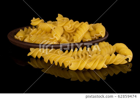 Yellow fusilli pasta isolated on black glass Yellow fusilli pasta isolated on black glass 62859474