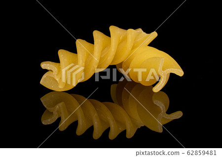 Yellow fusilli pasta isolated on black glass 62859481