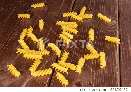 Yellow fusilli pasta on brown wood 62859482