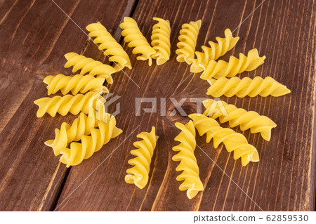 Yellow fusilli pasta on brown wood Yellow fusilli pasta on brown wood 62859530