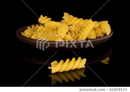 Yellow fusilli pasta isolated on black glass 62859533
