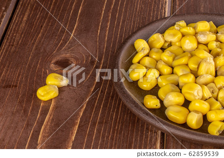 Yellow canned corn on brown wood 62859539