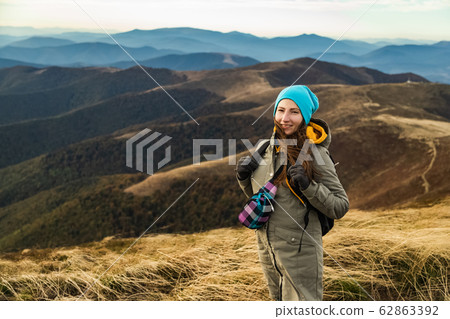 Woman the top of the mounting and looking at a beautiful landscape. Woman with backpack achieving the top the enjoying sunlit. 62863392