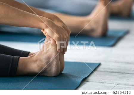 Closeup focus on woman feet and arms during Paschimottanasana pose 62864113