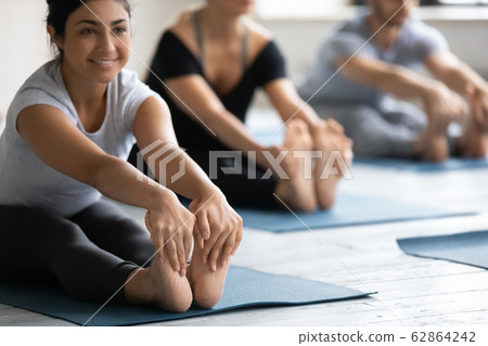 Indian woman doing Seated forward bend during yoga class Indian woman doing Seated forward bend during yoga class 62864242