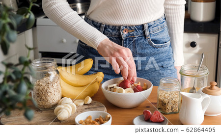 Adding fruits to breakfast oatmeal porridge bowl Adding fruits to breakfast oatmeal porridge bowl 62864405