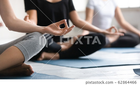 Focus on woman fingers folded in mudra gesture during meditation 62864466