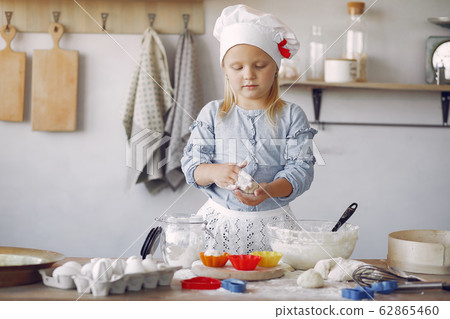 Little girl in a white shef hat cook the dough for cookies 62865460