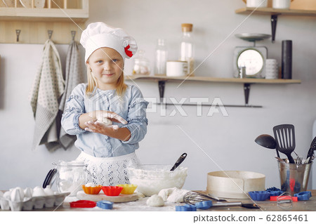 Little girl in a white shef hat cook the dough for cookies 62865461
