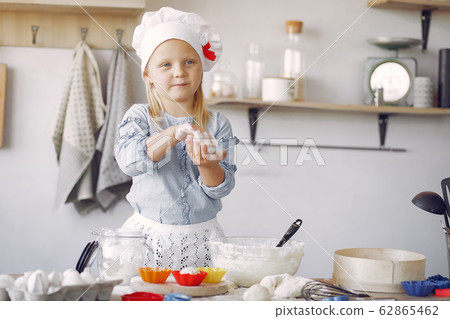 Little girl in a white shef hat cook the dough for cookies 62865462