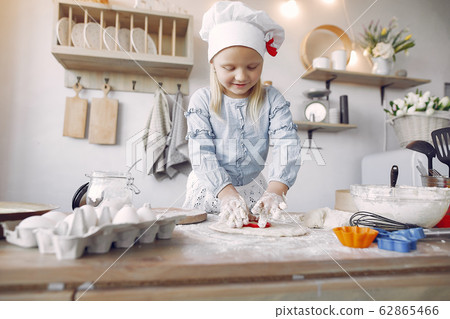 Little girl in a white shef hat cook the dough for cookies 62865466